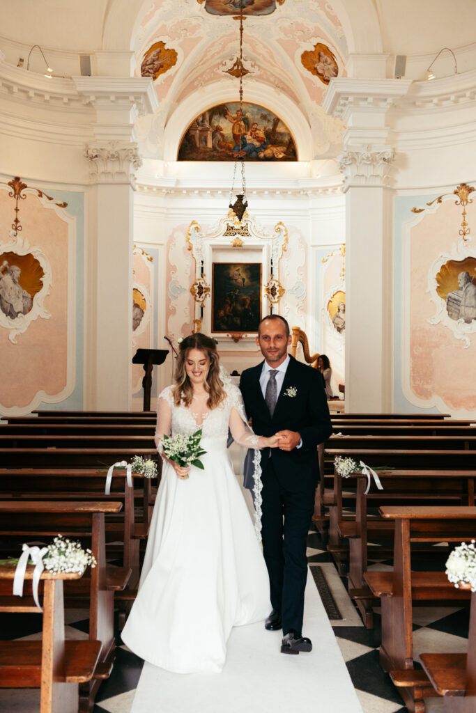 Newlyweds walking down the aisle together, just married in a romantic Italian castle.