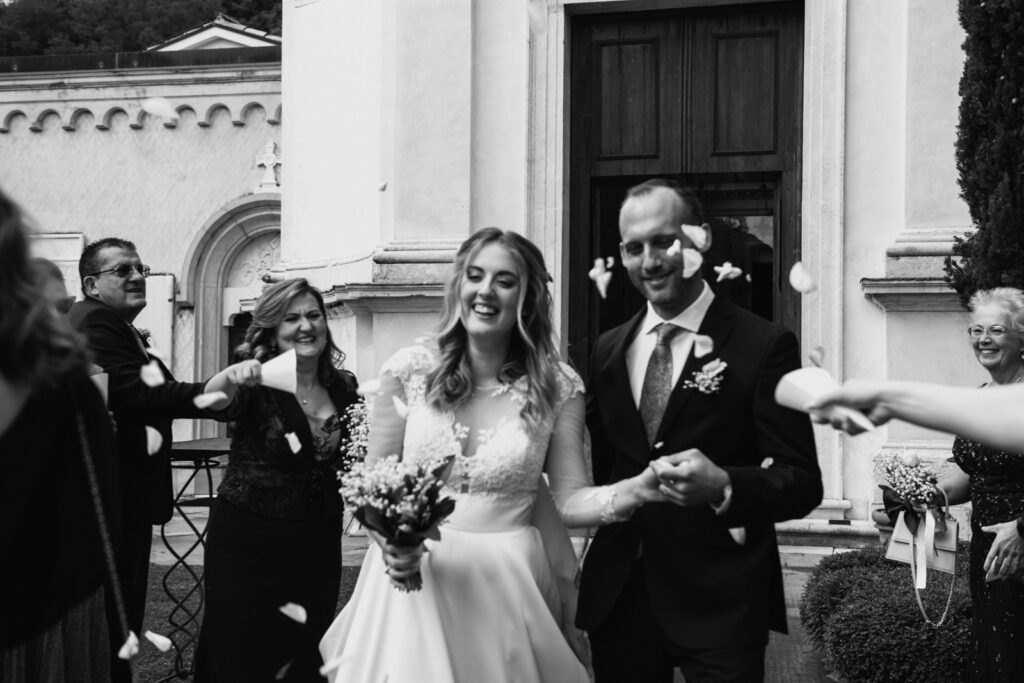 The newlyweds walking down the aisle of guests with petals falling around them.