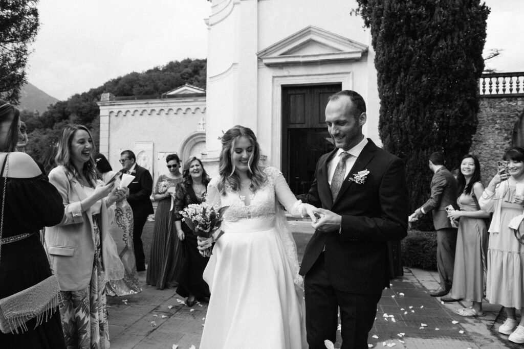 Bride and groom holding hands and laughing after the celebration outside the chapel.