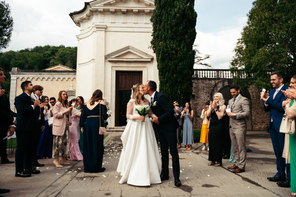 Bride and groom kissing after the ceremony, surrounded by their guests at CastelBrando.