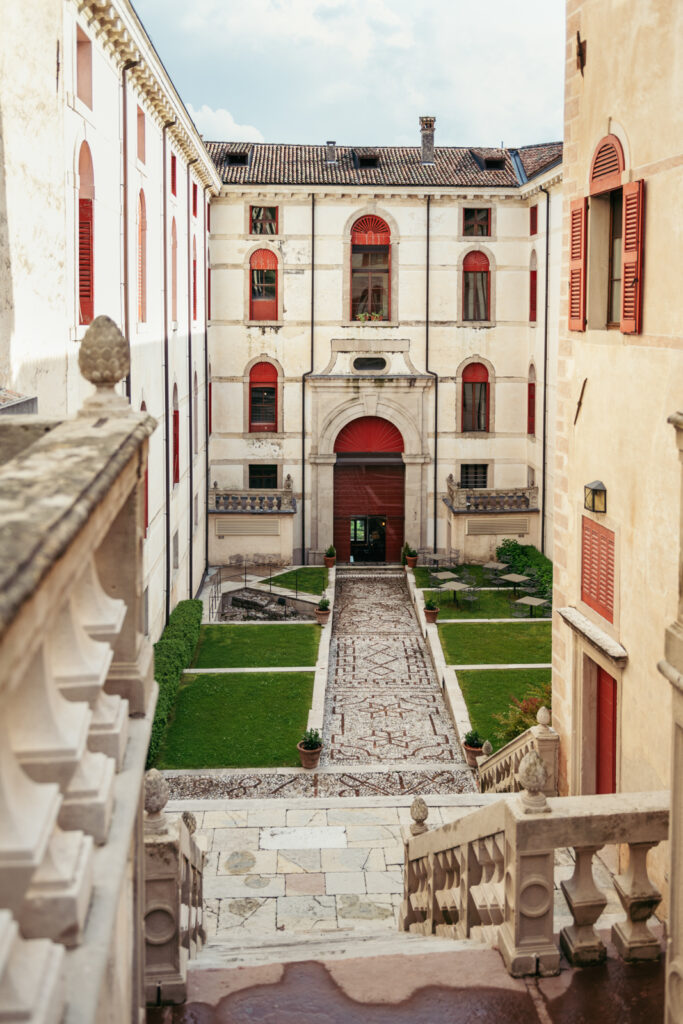 Castle terrace with red shutters and manicured gardens below.