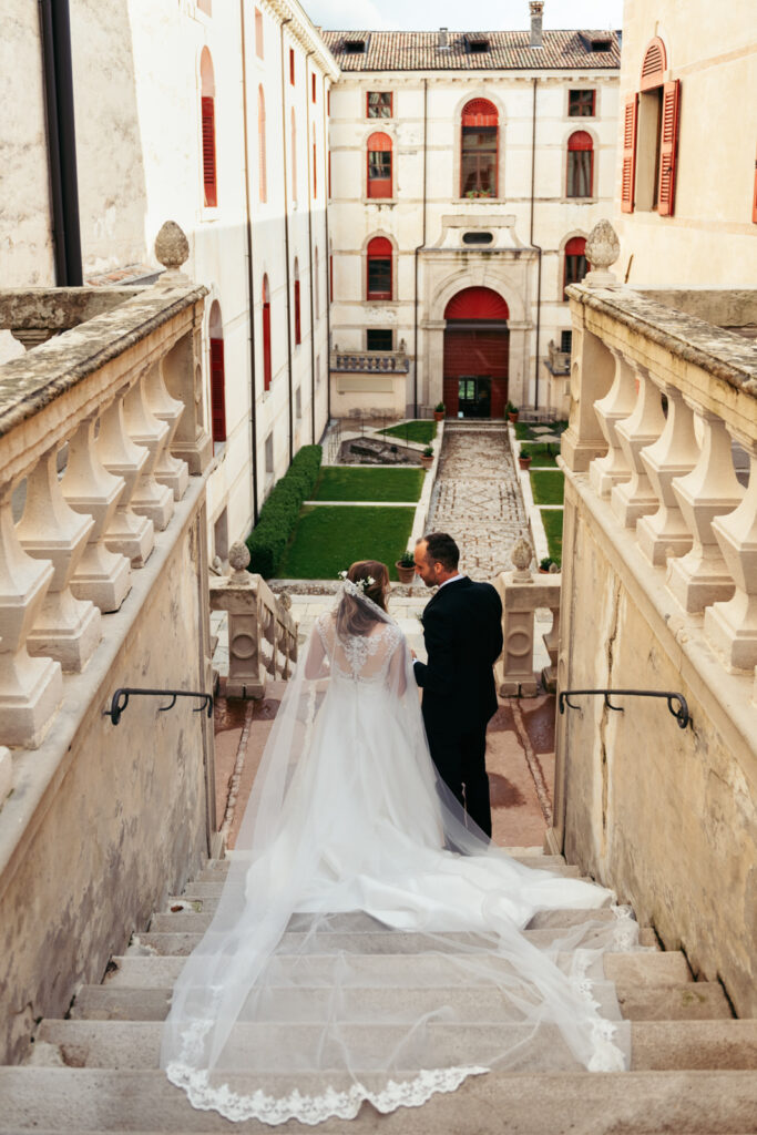 Bride and groom walking down the stairs, framed by the castle's symmetrical architecture.