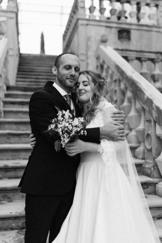 Couple hugging at the foot of CastelBrando’s grand staircase—Italy wedding dream location.