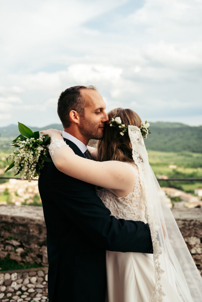 Groom hugging the bride with the Valdobbiadene hills in the background.