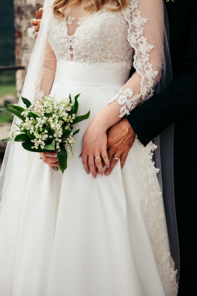 Close-up of the bride's bouquet and gown, with lily of the valley flowers.