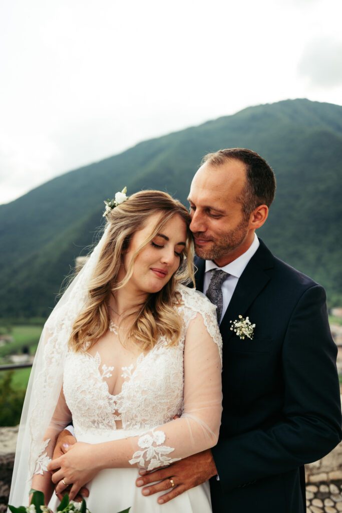 Bride resting her head on the groom’s shoulder, surrounded by mountain views.