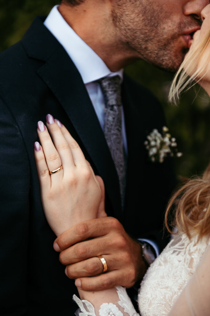 Detail of bride’s hand resting on the groom’s chest, showing her wedding ring.