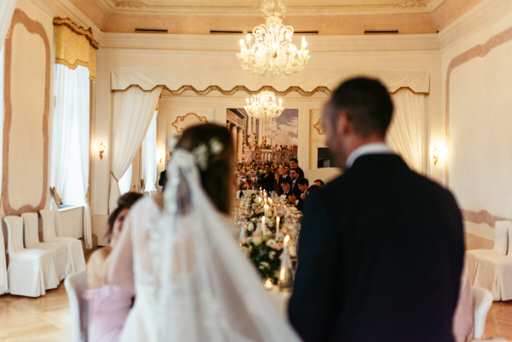 The bride entering the reception hall as guests stand to applaud.