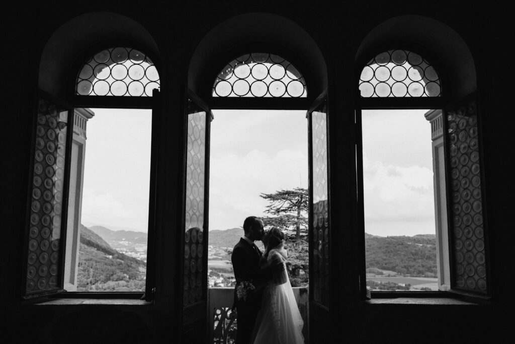Black and white photo of the newlyweds in the castle’s arched windows.