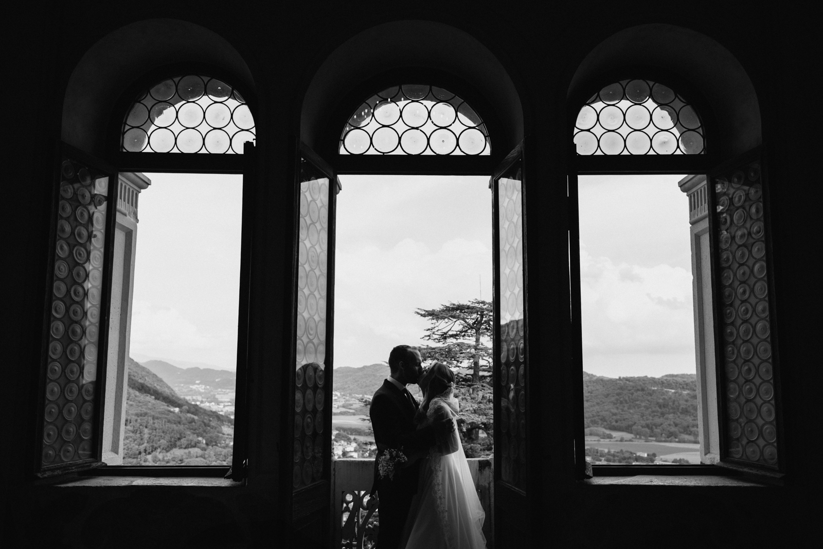 Black and white photo of the newlyweds in the castle’s arched windows.