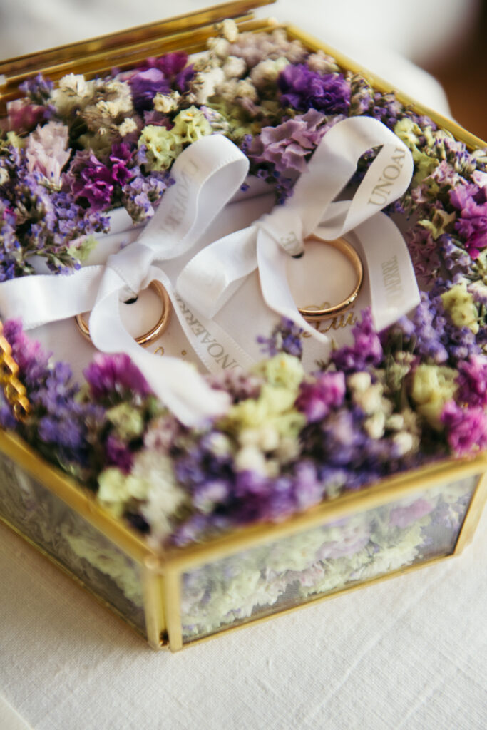 Wedding rings placed on dried flower petals with custom ribbons