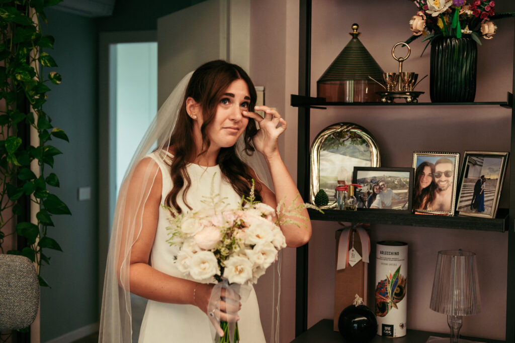 Bride in tears of joy while holding her bouquet before leaving for the ceremony