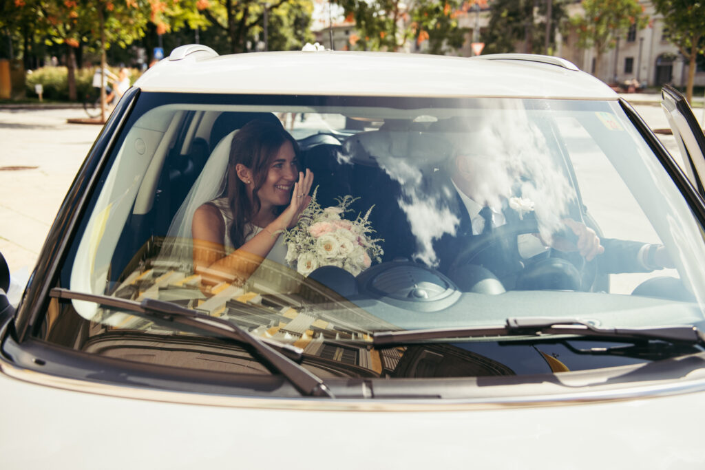 Bride seen through the windshield holding her bouquet on the way to the ceremony