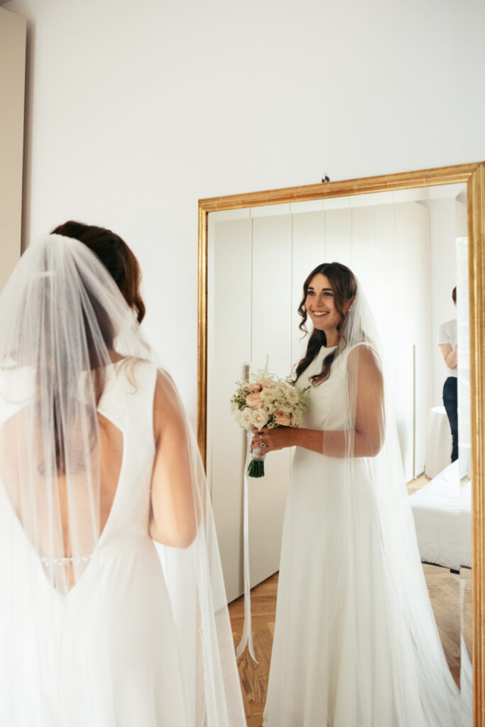 Bride smiling while looking at her reflection in the mirror