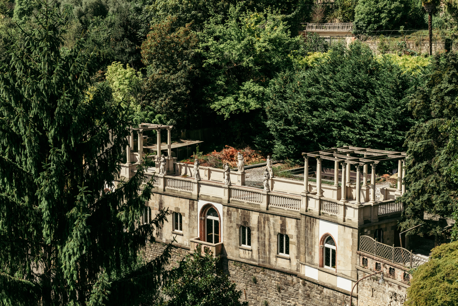 Quiet corner of the villa garden surrounded by trees and historic architecture