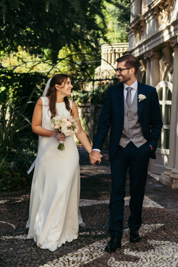 Newlyweds walking hand in hand through the shaded garden path