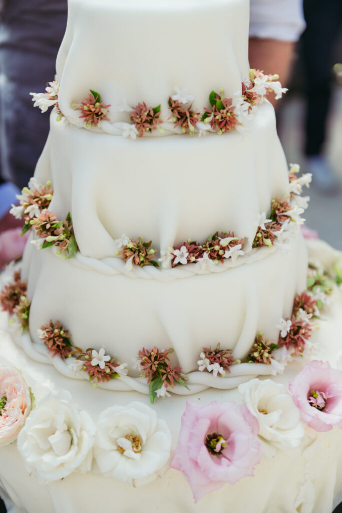 Close-up of a three-tier wedding cake decorated with fresh flowers and figs