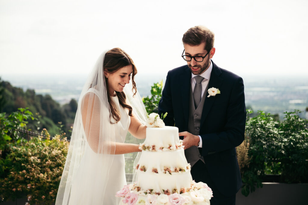 Bride holding the knife with groom by her side as they slice the wedding cake