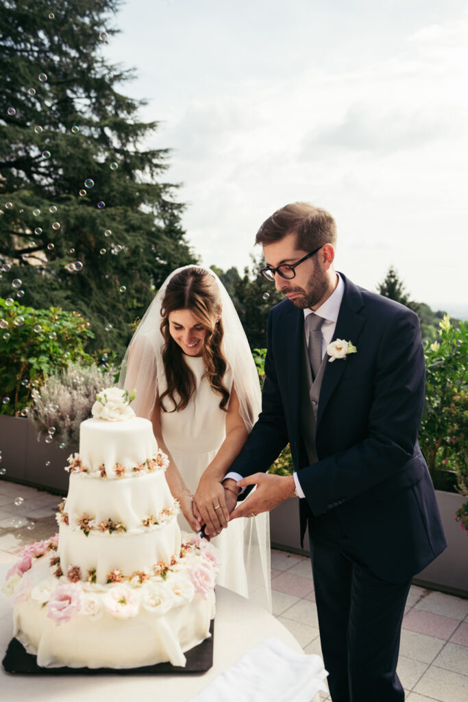 Bride and groom cutting their wedding cake together during the outdoor reception