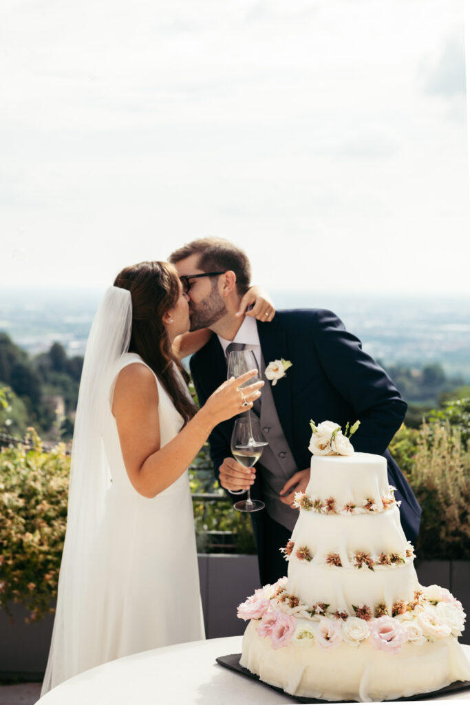 Newlyweds kissing after cutting the cake during their intimate Italian wedding