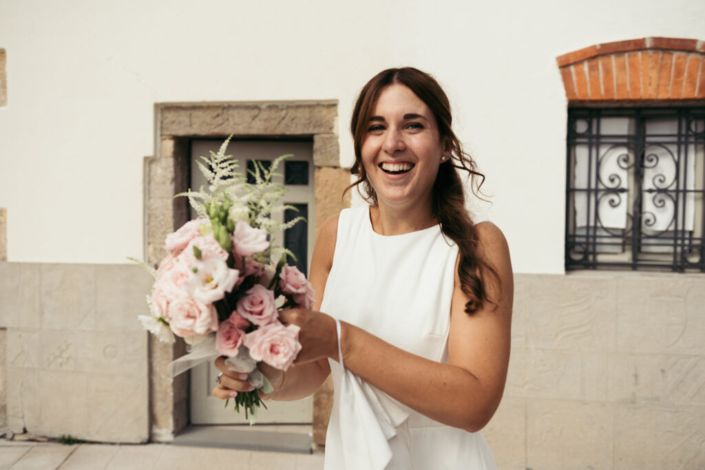 Bride smiling while holding her floral bouquet before the bouquet toss