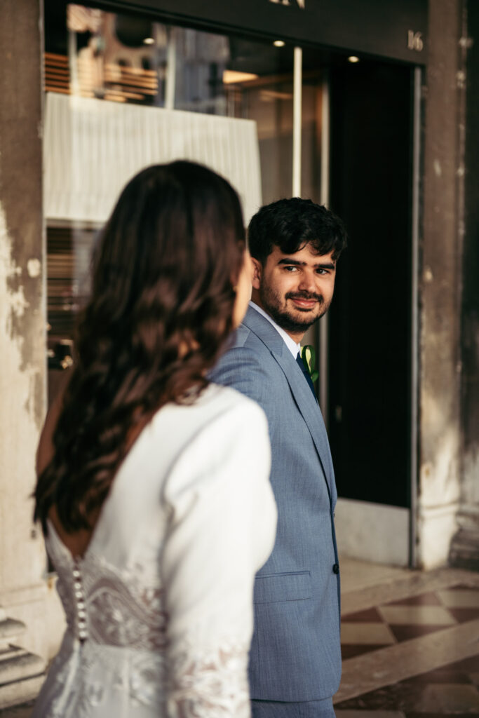 Bride walking toward groom while he smiles, captured after symbolic wedding in Venice