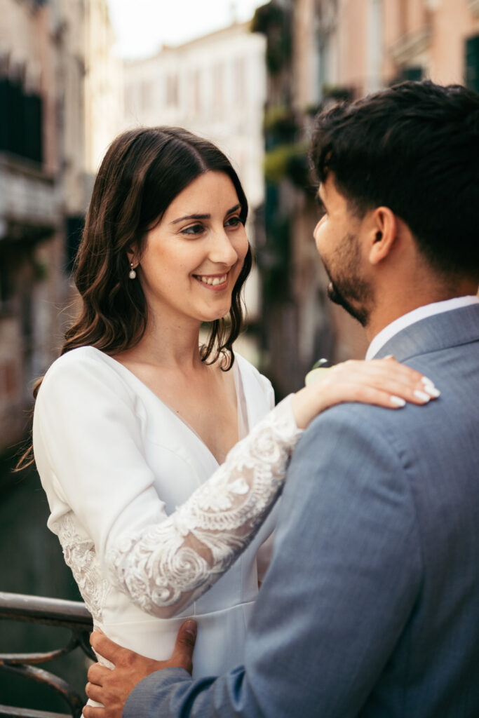 Bride smiling at groom during a quiet moment by the water in Venice