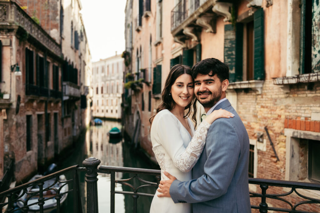 Couple holding each other by a canal railing during symbolic wedding photo session