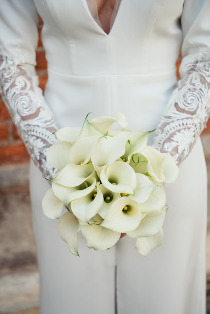 Close-up of bridal bouquet with white calla lilies and lace sleeves during symbolic wedding in Venice