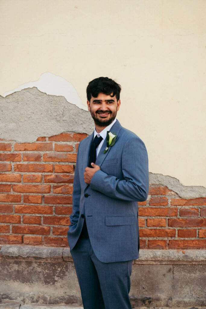 Groom portrait in front of a rustic Venetian wall before the gondola ceremony