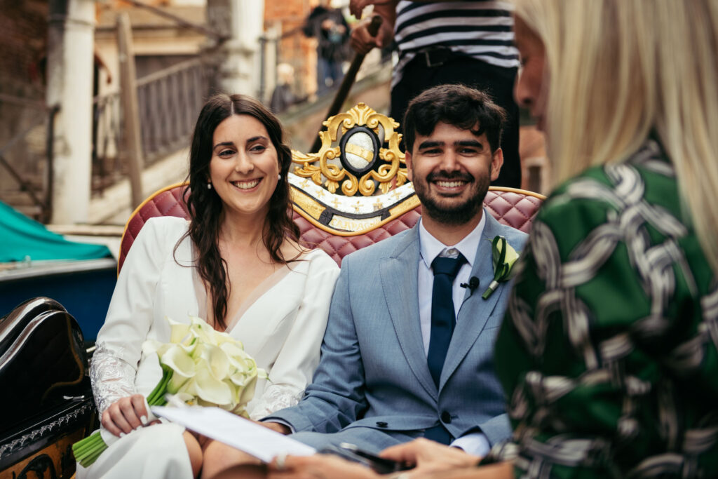 Bride smiling softly while holding her bouquet during intimate gondola ceremony