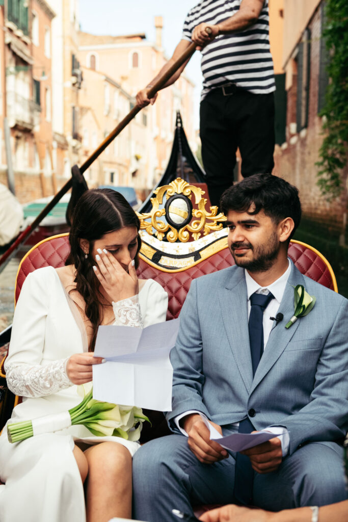 Groom listening tenderly as bride reads her vows during a gondola ceremony in Venice