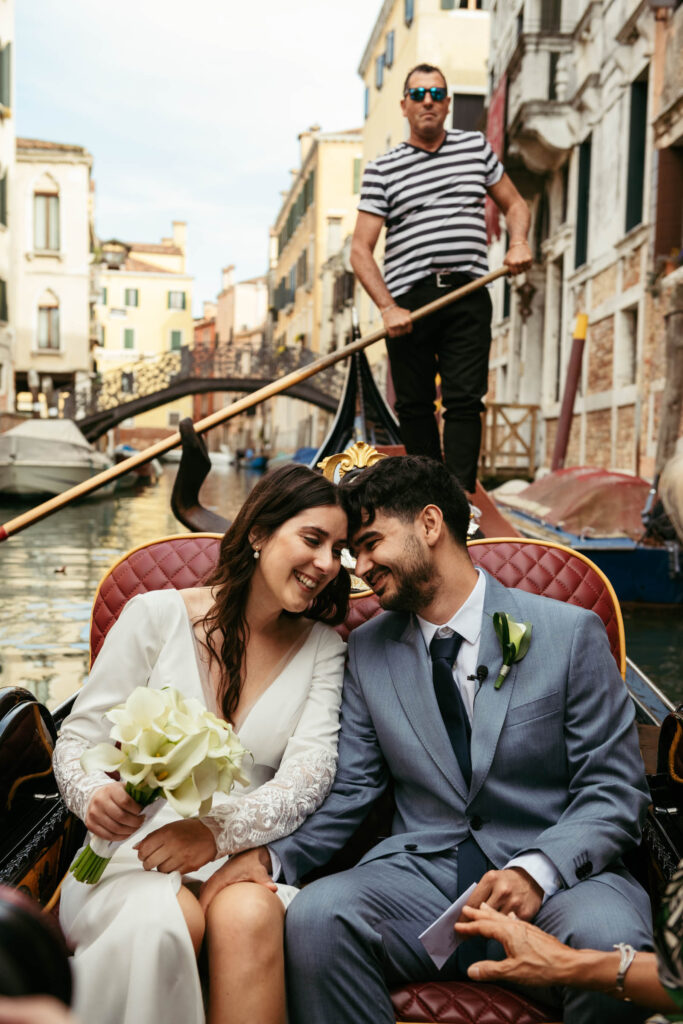 Couple laughing while exchanging rings during symbolic wedding on a gondola in Venice