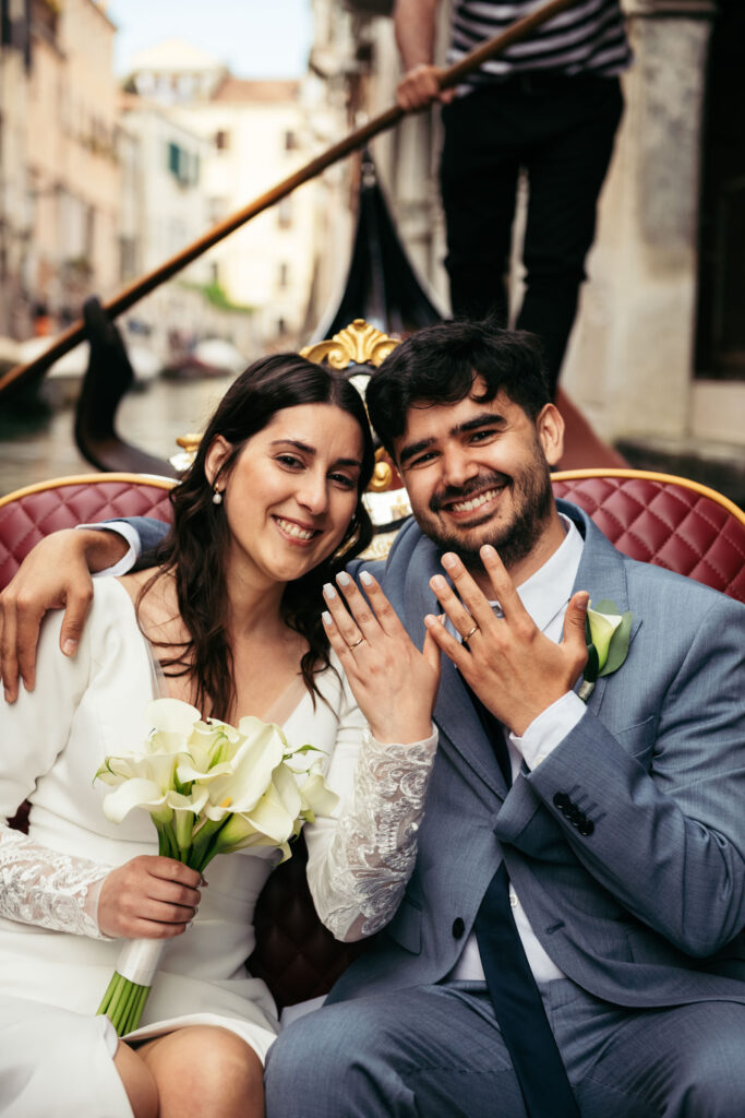 Happy bride and groom posing with their wedding bands during symbolic gondola ceremony