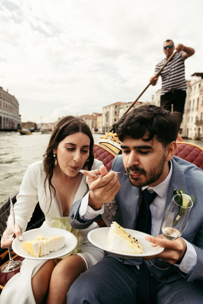 Bride and groom sharing wedding cake during symbolic gondola wedding in Venice