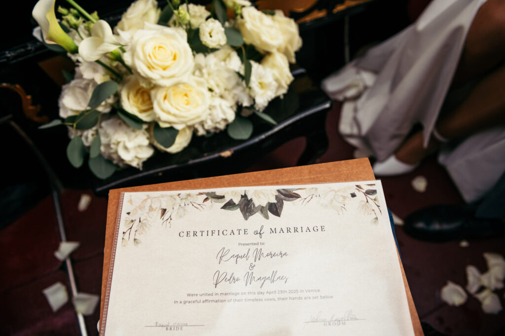 White wedding flowers and symbolic marriage certificate during a gondola elopement in Venice