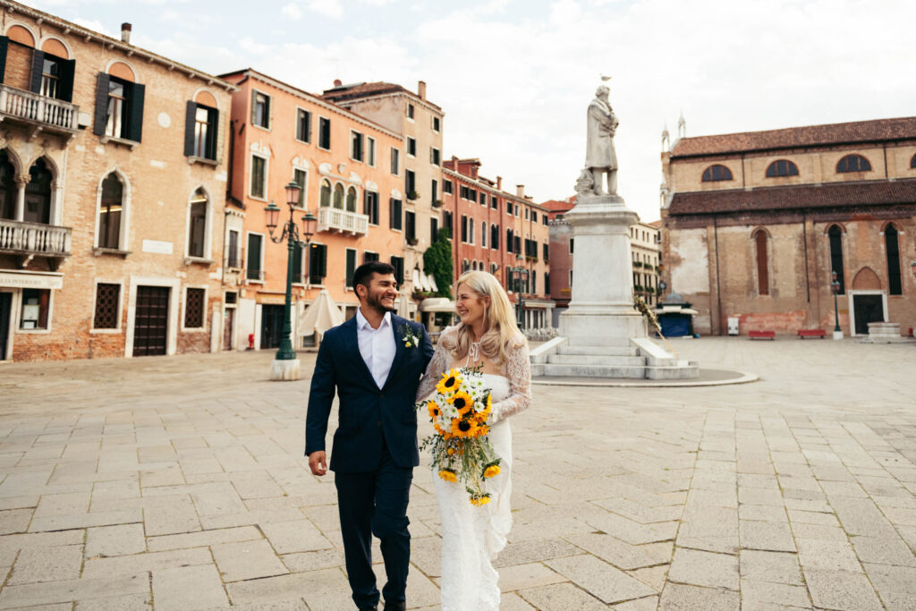 Groom and bride walking in a quiet Venetian square during their elopement morning