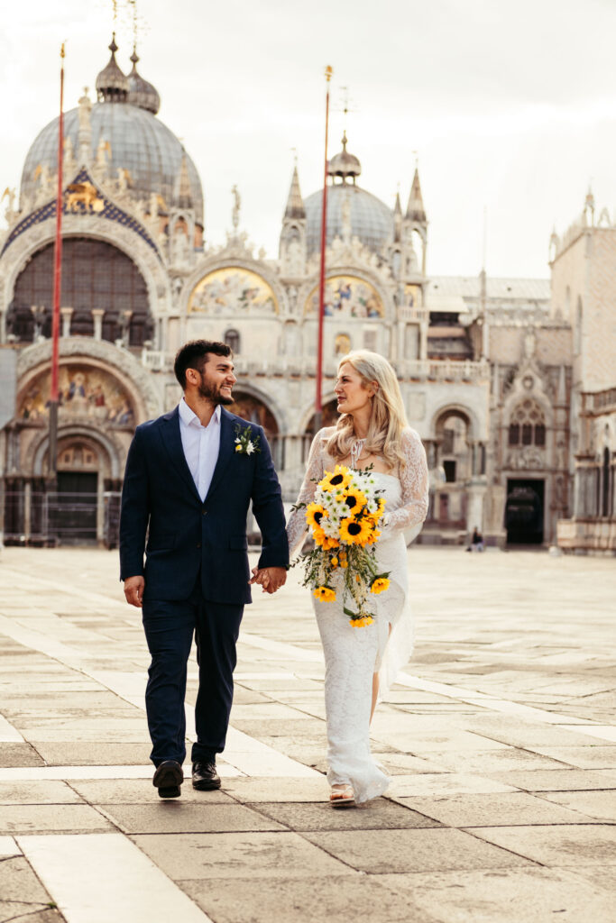 Holding hands in front of St. Mark’s Basilica during a symbolic elopement in Venice