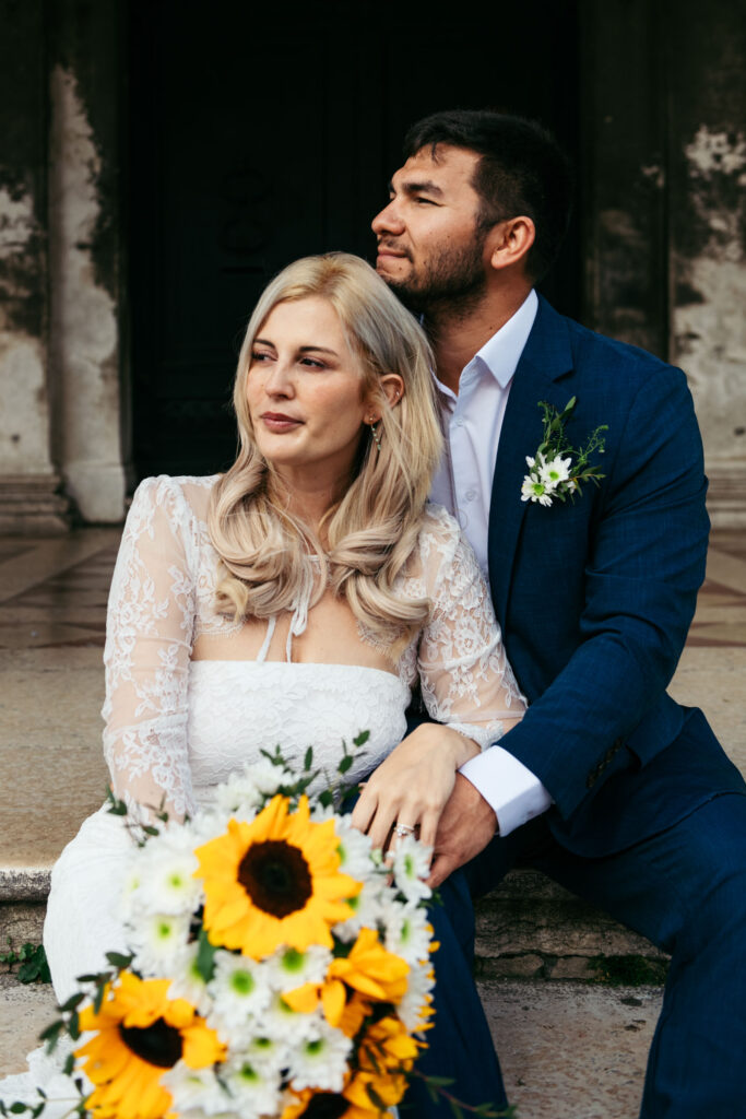 Bride sitting beside groom, holding sunflower bouquet during a quiet moment in their Venice elopement