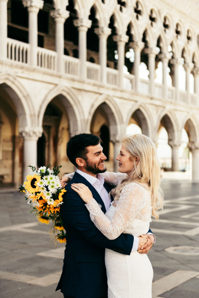 Bride looking at groom while holding bouquet of sunflowers in Piazza San Marco