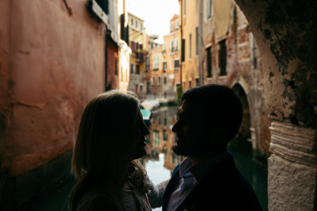 Silhouette of the couple in a narrow Venetian alley during golden hour
