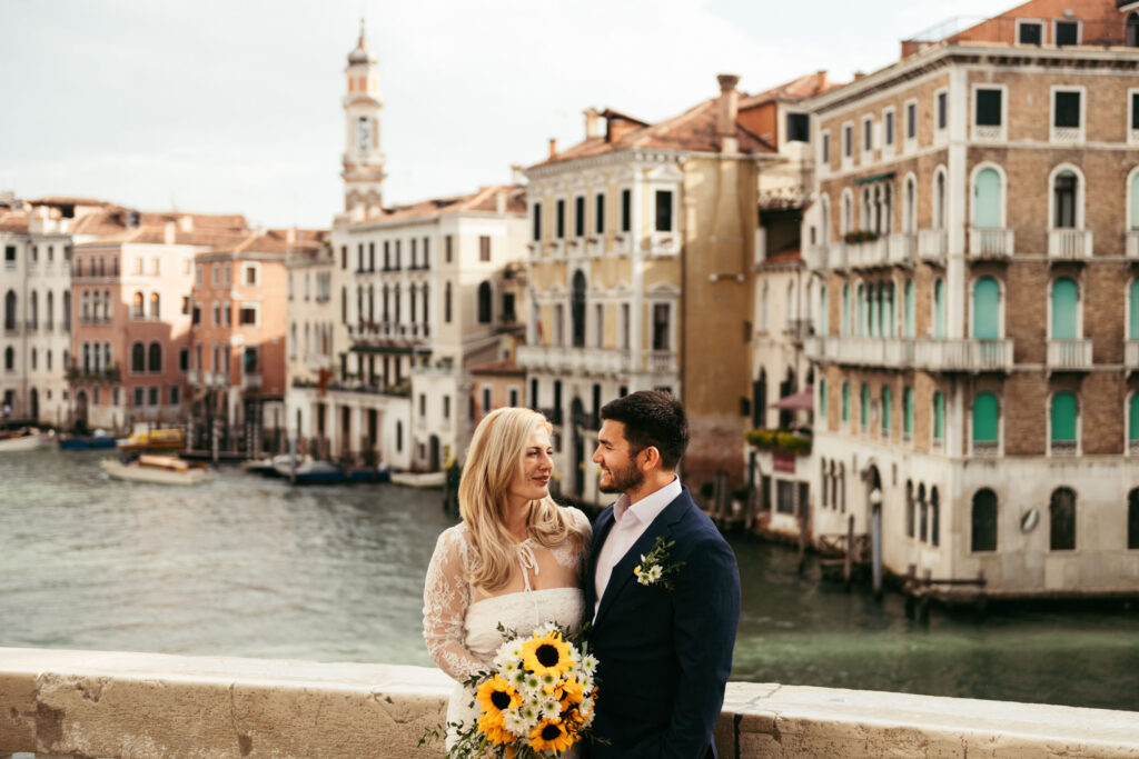 Bride and groom standing on a bridge overlooking the Grand Canal in Venice