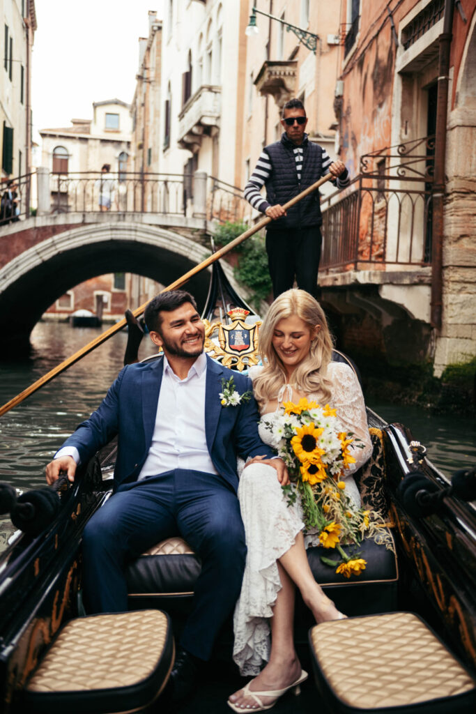 Bride and groom smiling during a gondola ride through the canals after their elope in Venice