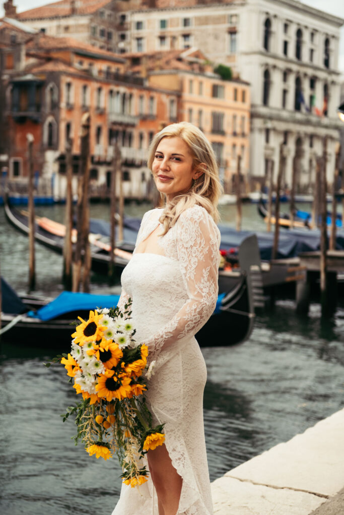 Bride standing by the water holding her bouquet after the gondola ride