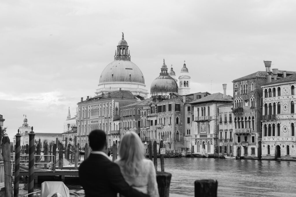 Bride and groom admiring the view of Santa Maria della Salute from the edge of the canal
