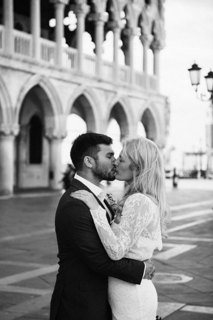Couple sharing a kiss under the arches of the Doge’s Palace in a quiet moment