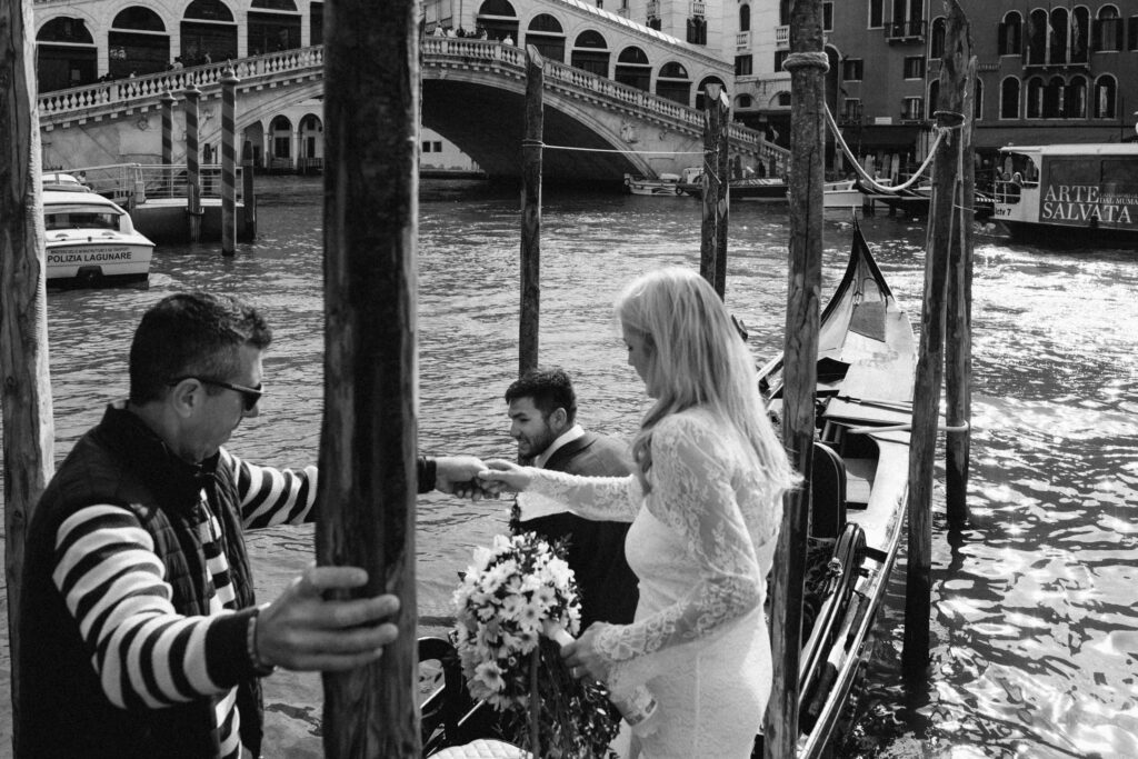 Black and white photo of the couple boarding a gondola near the Rialto Bridge in Venice